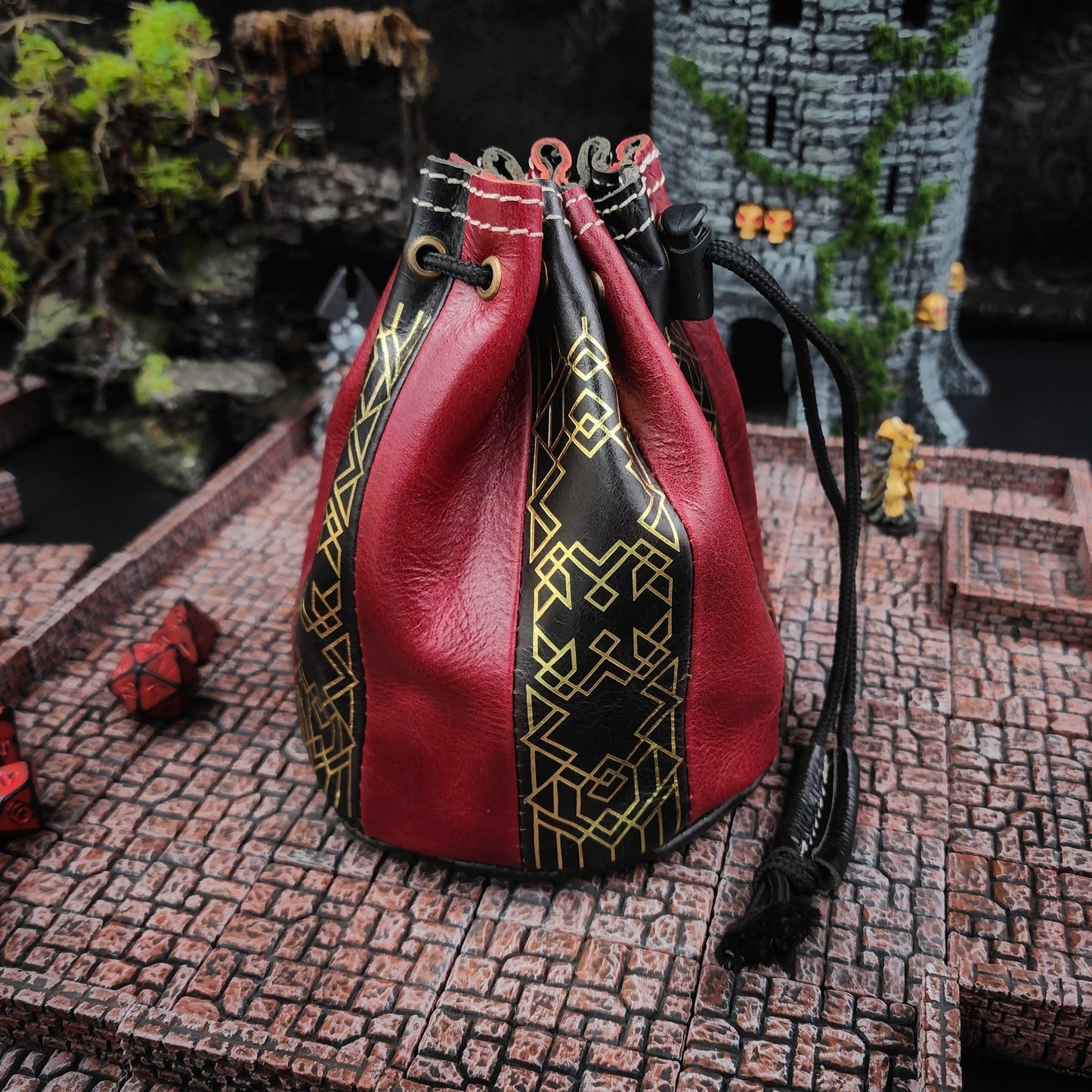 Handcrafted black and red buffalo hide standing round D&D dice bag with gilded Dwarven line work design by Grimbeard Leather.