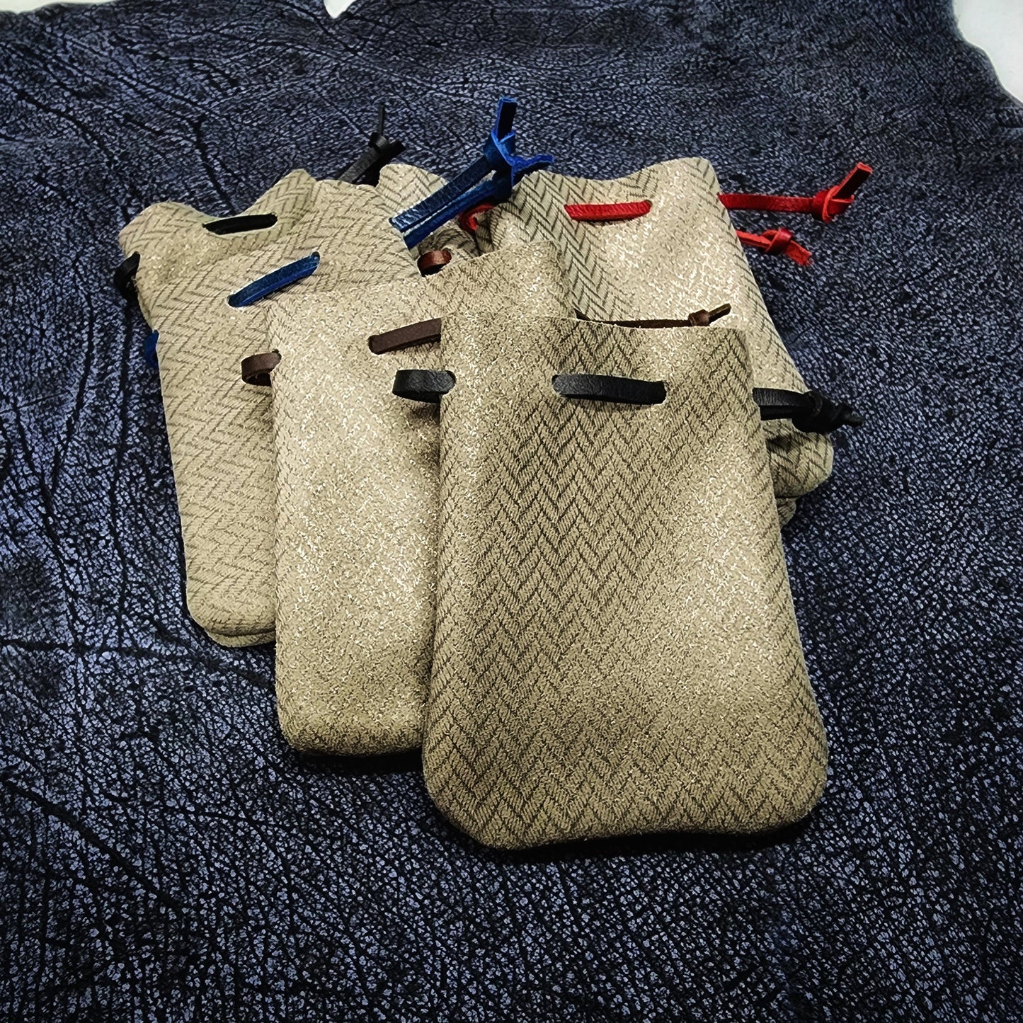 Handcrafted small embossed and patterned leather dice bags with gilded accents for D&D players and retail store counters.
