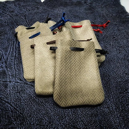Handcrafted small embossed and patterned leather dice bags with gilded accents for D&D players and retail store counters.