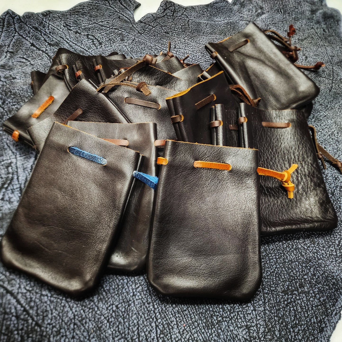 Handcrafted small flat leather dice bags in a bulk random assortment for D&D game shops and Renaissance festival vendor counters.