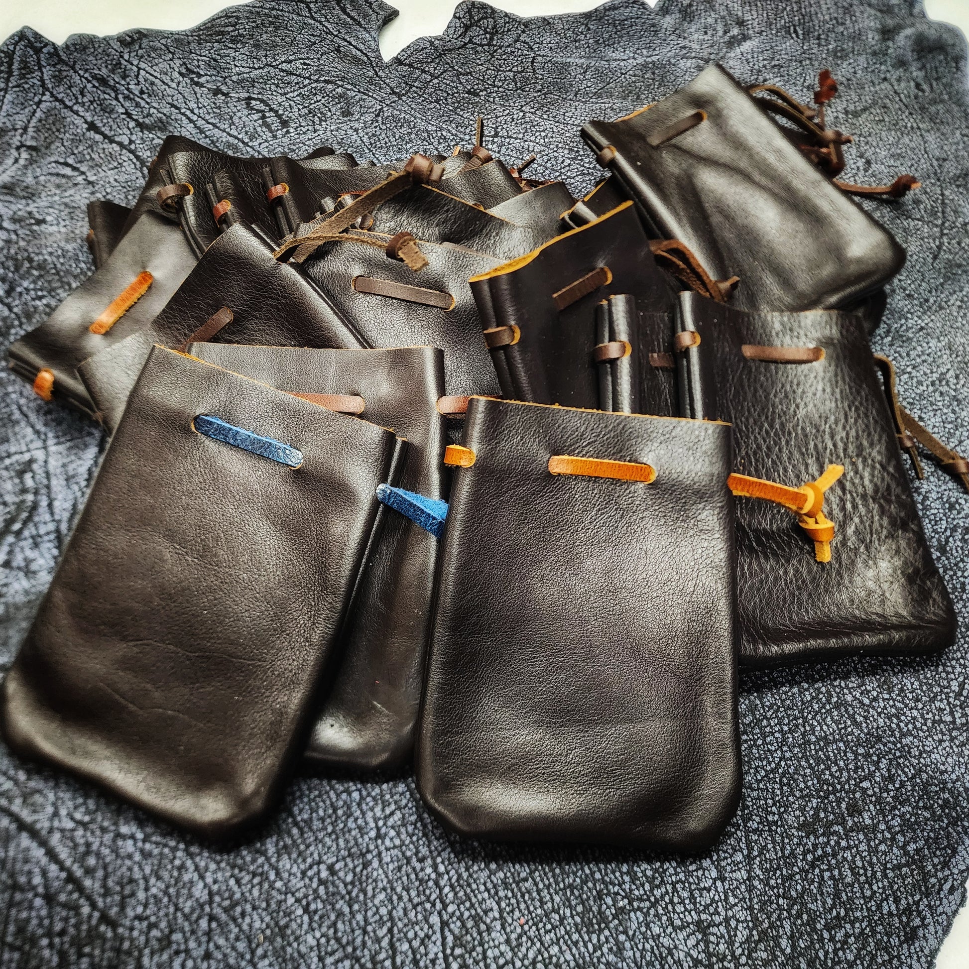 Handcrafted small flat leather dice bags in a bulk random assortment for D&D game shops and Renaissance festival vendor counters.