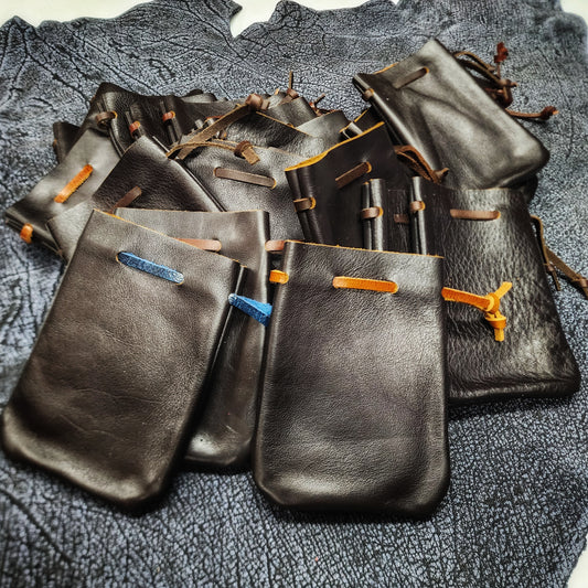 Handcrafted small leather dice bags in earthtones, blacks, and browns for D&D players and retail store counters.
