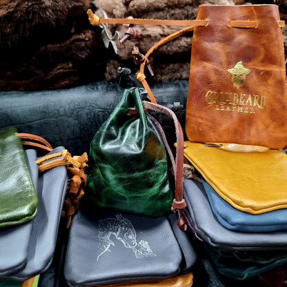 Handcrafted small flat leather dice bags in a bulk random assortment for D&D game shops and Renaissance festival vendor counters.