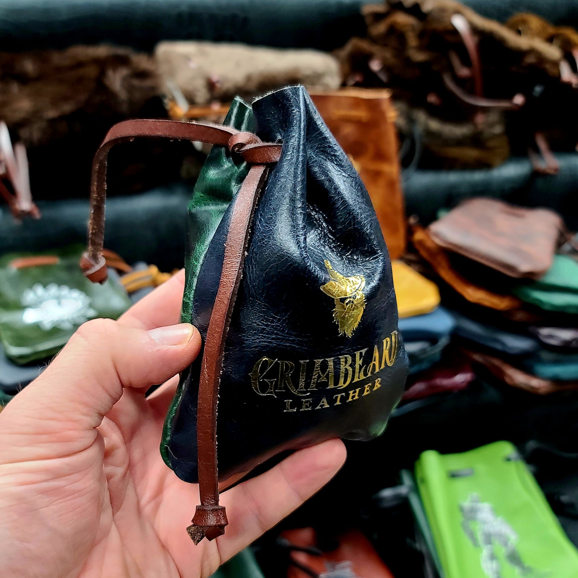 Handcrafted small flat leather dice bags in a bulk random assortment for D&D game shops and Renaissance festival vendor counters.
